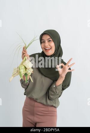 donna con ketupat su sfondo bianco. donna musulmana hijab su eid ramadan con torta di riso piatto tradizionale Foto Stock