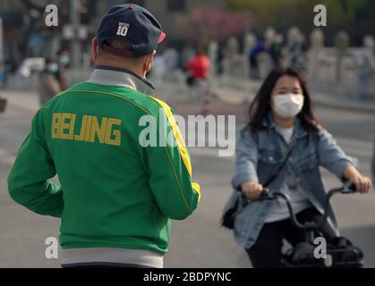 Pechino, Cina. 9 aprile 2020. I cinesi che indossano maschere facciali protettive cavalcano le loro biciclette a Pechino il giovedì 9 aprile 2020. La capitale cinese sta rallentando il ritorno alla vita "normale" dalle misure di sicurezza draconiane a causa dell'epidemia di Covid-19, mentre il governo solleva lentamente alcune restrizioni sui viaggi e sulle interazioni sociali. Foto di Stephen Shaver/UPI Credit: UPI/Alamy Live News Foto Stock