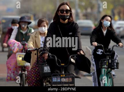 Pechino, Cina. 9 aprile 2020. I cinesi che indossano maschere facciali protettive cavalcano le loro biciclette a Pechino il giovedì 9 aprile 2020. La capitale cinese sta rallentando il ritorno alla vita "normale" dalle misure di sicurezza draconiane a causa dell'epidemia di Covid-19, mentre il governo solleva lentamente alcune restrizioni sui viaggi e sulle interazioni sociali. Foto di Stephen Shaver/UPI Credit: UPI/Alamy Live News Foto Stock