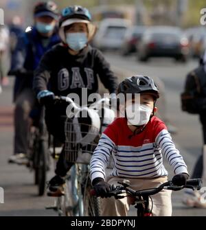 Pechino, Cina. 9 aprile 2020. Una famiglia che indossa maschere facciali protettive ride le loro biciclette a Pechino il giovedì 9 aprile 2020. La capitale cinese sta rallentando il ritorno alla vita "normale" dalle misure di sicurezza draconiane a causa dell'epidemia di Covid-19, mentre il governo solleva lentamente alcune restrizioni sui viaggi e sulle interazioni sociali. Foto di Stephen Shaver/UPI Credit: UPI/Alamy Live News Foto Stock