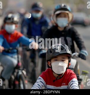 Pechino, Cina. 9 aprile 2020. Una famiglia che indossa maschere facciali protettive ride le loro biciclette a Pechino il giovedì 9 aprile 2020. La capitale cinese sta rallentando il ritorno alla vita "normale" dalle misure di sicurezza draconiane a causa dell'epidemia di Covid-19, mentre il governo solleva lentamente alcune restrizioni sui viaggi e sulle interazioni sociali. Foto di Stephen Shaver/UPI Credit: UPI/Alamy Live News Foto Stock