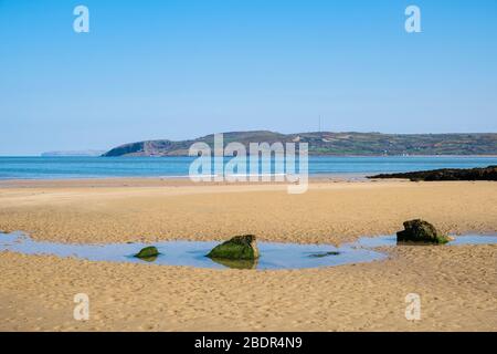 Una piscina marea su una bellissima spiaggia di sabbia tranquilla con vista su Llanddona attraverso la Baia di Red Wharf. Bennlech, Isola di Anglesey, Galles del Nord, Regno Unito, Gran Bretagna Foto Stock