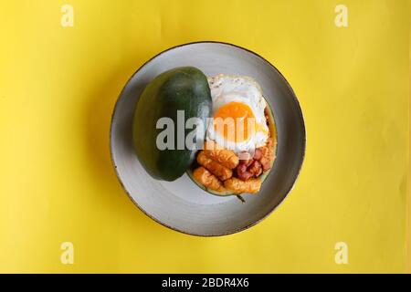 Vista dall'alto riso fritto con uova e salsiccia soleggiate in contenitore di anguria con sfondo giallo Foto Stock