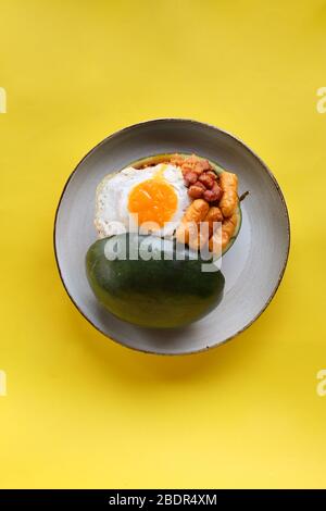 Vista dall'alto riso fritto con uova e salsiccia soleggiate in contenitore di anguria con sfondo giallo Foto Stock