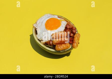 Riso fritto con uovo soleggiato e salsiccia in contenitore di anguria con sfondo giallo Foto Stock