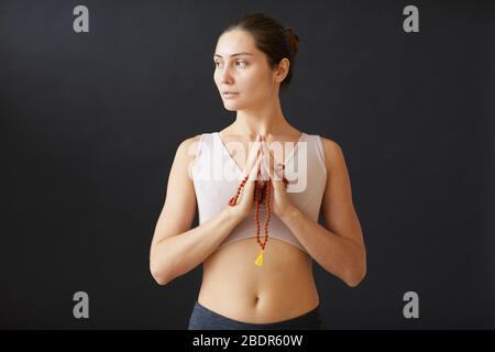 Ritratto di giovane bella donna in piedi in posa yoga su sfondo nero Foto Stock