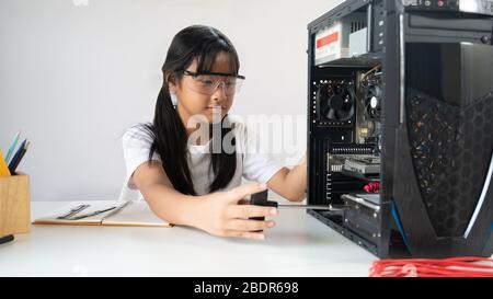 Foto di adorabile scuola ragazza imparare a riparare un hardware computer che mettere su bianco scrivania di lavoro con cacciavite e attrezzature tecniche su wh Foto Stock