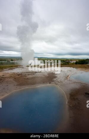 Una piscina blu calda di fronte ai geyser a Geysir in Islanda Foto Stock