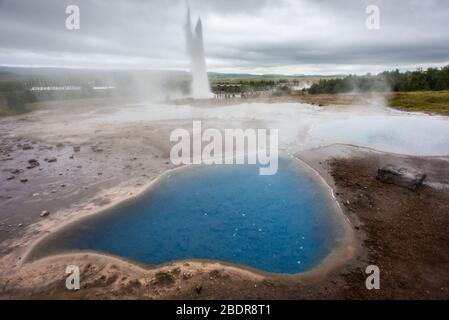 Una piscina blu calda di fronte ai geyser a Geysir in Islanda Foto Stock