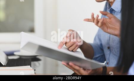 Immagine ritagliata del team di sviluppo aziendale che discute/incontra sul risultato del profitto aziendale mentre tiene un file di documento e si siede in modalità Foto Stock