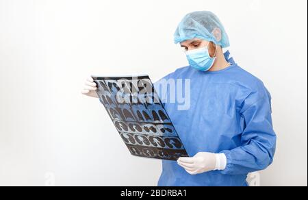 Medico chirurgo in controllo uniforme protettivo su pellicola di raggi X di risonanza magnetica polmoni scansione. Coronavirus Covid 19, polmonite, tubercolosi, cancro polmonare, respiratorio Foto Stock