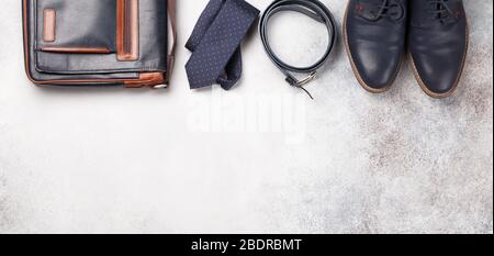 Set di abiti classici da uomo come cravatta, cintura, scarpe e borsa su sfondo di pietra con spazio copia. Vista dall'alto, disposizione piatta Foto Stock