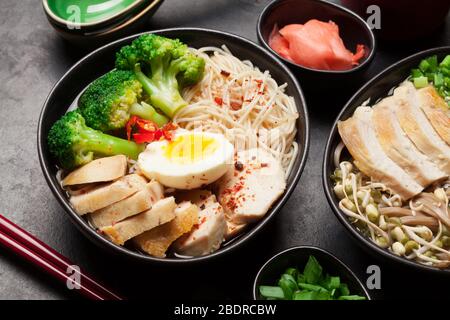 Zuppa asiatica di ramen con pollo, verdure e uova su sfondo di pietra Foto Stock