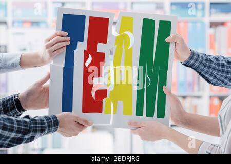 Uomini d'affari che assemblano un puzzle, stanno tenendo i pezzi e li collegano insieme: Lavoro di squadra e concetto di cooperazione Foto Stock