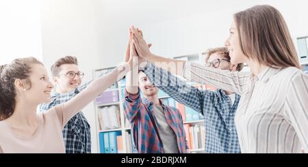 I giovani si riuniscono in ufficio e si uniscono le mani, la cooperazione e il concetto di lavoro di squadra Foto Stock