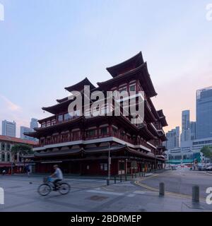 Singapore - 31 Ott 2019: Un uomo guida una bicicletta di fronte al Tempio Cinese Relic del dente di Buddha, all'alba, nel centro di Singapore Foto Stock