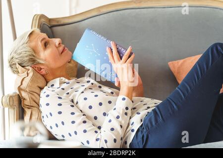 Donna che tiene un libro di astrologia con entrambe le mani Foto Stock