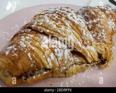 Delizioso croissant francese con ripieno di cioccolato e zucchero in polvere Foto Stock