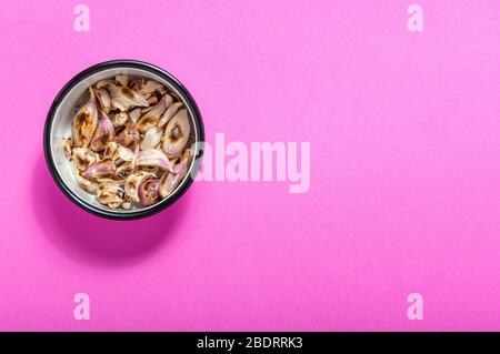 Aglio arrosto in una ciotola di smalto su sfondo rosa. Isolato su rosa. Ingredienti alimentari Foto Stock