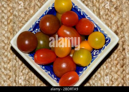 Ciotola quadrata riempita con vari colori di pomodori ciliegini Foto Stock