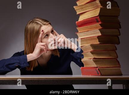 Ritratto di una ragazza con libri. Questa ragazza è un po 'scioccata alla quantità di libri che deve leggere Foto Stock