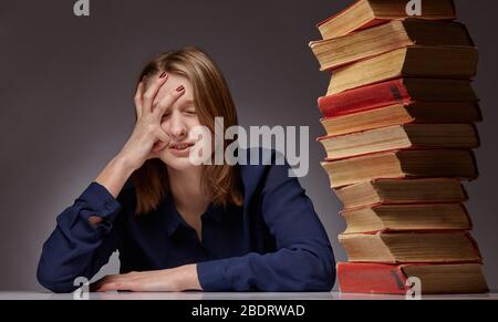 Ritratto di una ragazza con libri. Questa ragazza è un po 'scioccata alla quantità di libri che deve leggere Foto Stock