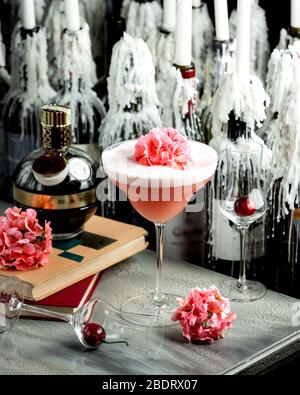 cocktail rosa in vetro a stelo lungo guarnito con un fiore Foto Stock