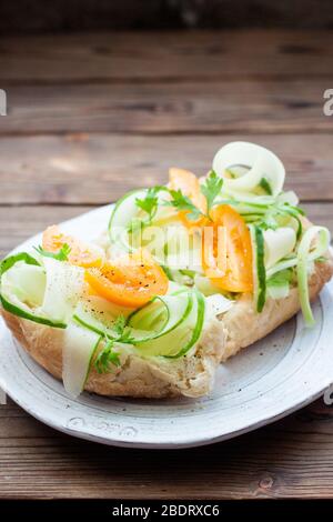 Bruschetta con cetrioli, pomodori, finocchio e formaggio cremoso su sfondo rustico in legno. Colazione sana. Foto Stock