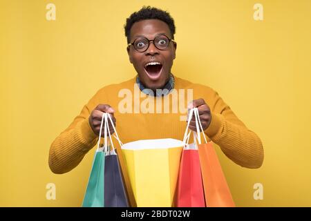Bel giovane afro-americano tiene borse di carta per lo shopping Foto Stock