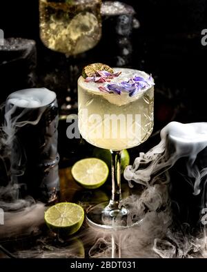 un cocktail di lime in vetro di cristallo guarnito con petali di fiori    Foto Stock