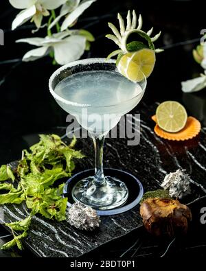 un bicchiere di cocktail di lime guarnito con fette di lime e scorza Foto Stock