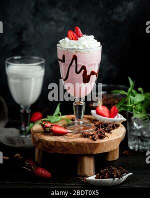 un bicchiere di frullato di fragole con panna montata e fragola Foto Stock