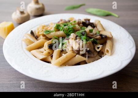 Vegano cremoso aglio a fungo con cipolle rosse guarnite con basilico in un piatto bianco con i suoi ingredienti sullo sfondo Foto Stock