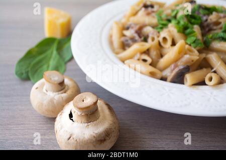 Vegano cremoso aglio a fungo con cipolle rosse guarnite con basilico in un piatto bianco con i suoi ingredienti sullo sfondo Foto Stock