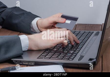 Un giovane effettua acquisti online da casa con una carta di credito. Negozio online. Foto Stock