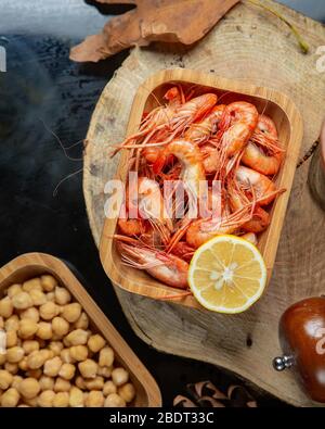 vista superiore dei gamberi bolliti serviti con metà limone in bambù Foto Stock