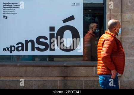 Annuncio bancario del conto di espansione. Una persona con una maschera per il coronavirus a Las Ramblas praticamente deserta a causa del confinamento totale Foto Stock