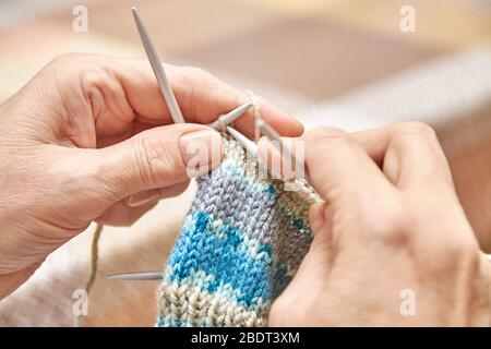 Donna maglia calzini. Un hobby di donna anziana è la maglieria. Vista in primo piano del circuito di maglieria. Messa a fuoco selettiva Foto Stock
