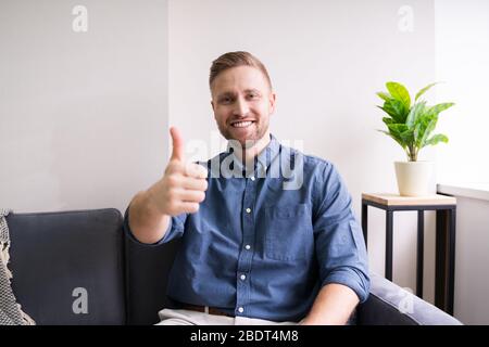 Ritratto di UN giovane uomo felice che mostra le pollice in su a casa Foto Stock