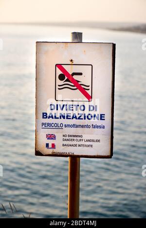 Primo piano del cartello "No Swimming Danger Cliff" in italiano, inglese e francese Foto Stock