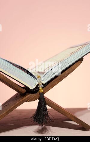 Quran aperto in placemat di legno. Mese Santo nel mondo musulmano - Ramadan Kareem. Concetto EID-al-adha. Legno Rehal con libro sacro aperto Quran e rosario Foto Stock