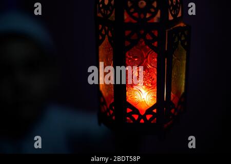 Ragazzo musulmano che tocca la tradizionale candela di lanterna araba che soffia al buio. Ragazzo mediorientale che prega. Ringraziando dio. Ramadan, Eid-al-Adha concetti Foto Stock