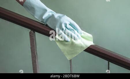 Vista in primo piano della mano di una donna con un panno antibatterico bagnato per disinfettare la ringhiera sulla gabbia volante. Foto Stock