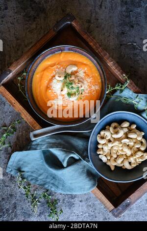 Zuppa di patate dolci cremosa con pecorino, noci di cashew arrosto e timo fresco in una ciotola di ceramica Foto Stock
