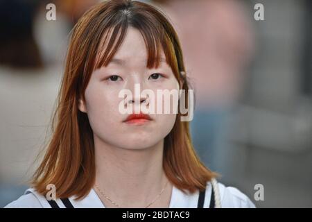 Giovane donna cinese che guarda serious in Jianghan Road, Wuhan, Cina Foto Stock