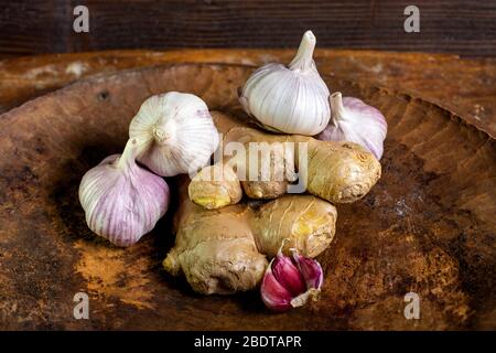 Zenzero fresco e aglio in una ciotola di legno Foto Stock