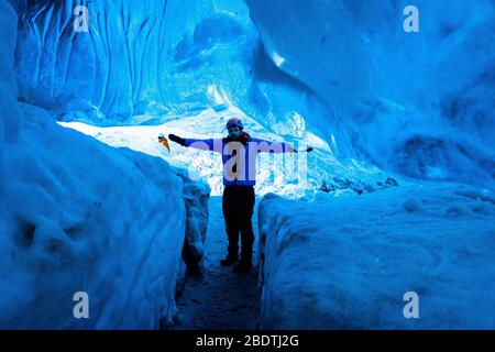 un esploratore maschile in una grotta di ghiaccio sul ghiacciaio, Islanda Foto Stock