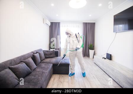La disinfezione in tuta protettiva conduce la disinfezione in casa per prevenire il coronavirus. Auto sanitaria. Foto Stock