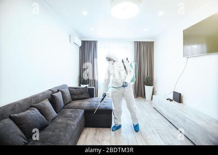 La disinfezione in tuta protettiva conduce la disinfezione in casa per prevenire il coronavirus. Auto sanitaria. Foto Stock