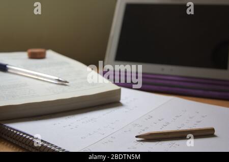 Immagine della scrivania di uno studente che si prepara per gli esami a casa, davanti allo schermo di un tablet connesso a Internet Foto Stock